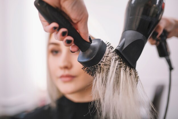 Estilista de la cosecha que seca el pelo con el cepillo