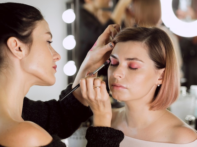 Estilista encantadora aplicando sombra de ojos