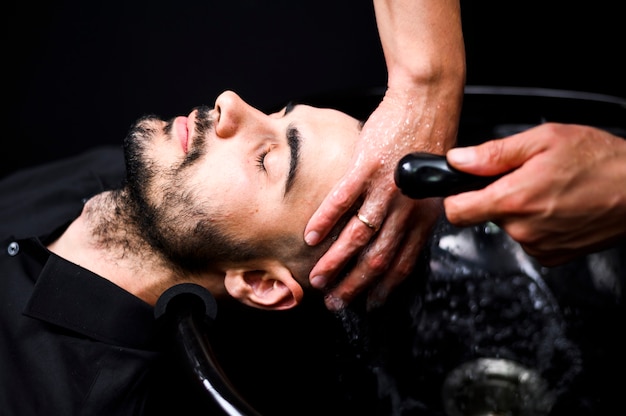 Estilista lavando el cabello del cliente en el salón