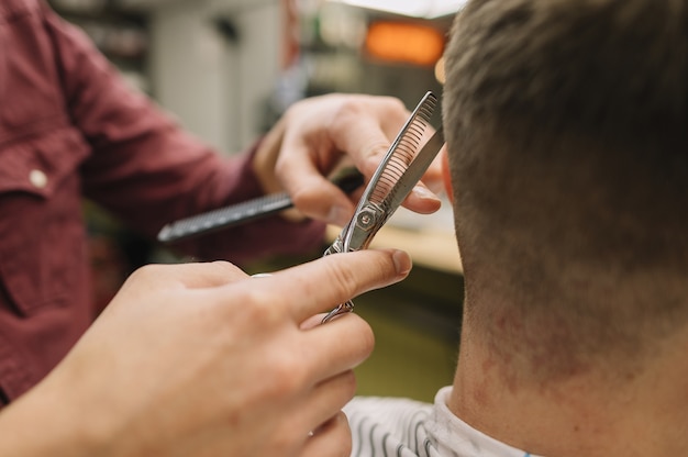 Foto gratuita estilista de primer plano dando un corte de pelo a un cliente