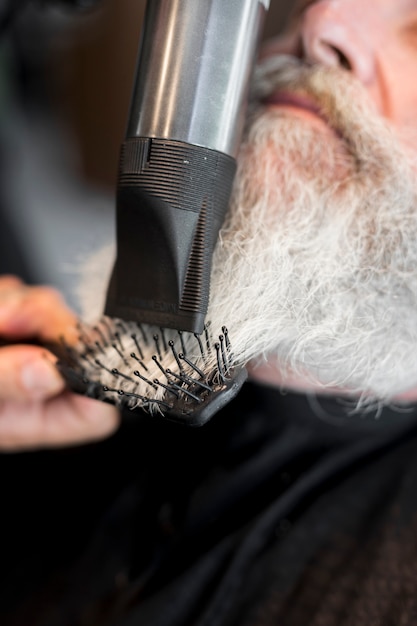 Estilista que hace la barba de estilo para el cliente en el salón