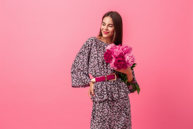 Estilo de mujer en vestido con flores sobre fondo rosa