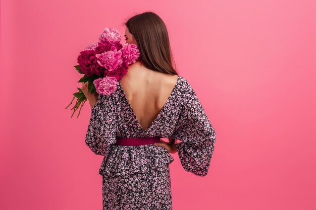 Estilo de mujer en vestido con flores sobre fondo rosa