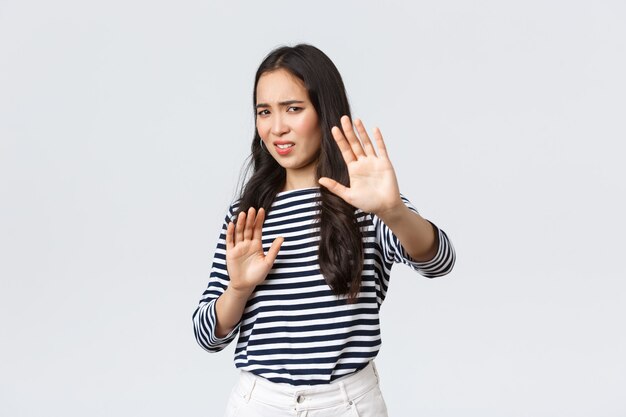 Estilo de vida, belleza y moda, concepto de emociones de personas. La mujer se siente incómoda al ser fotografiada, pide que apague la cámara, levanta las manos a la defensiva, protege el rostro de la linterna