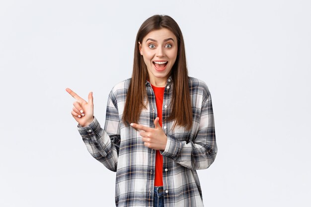 Estilo de vida, diferentes emociones, concepto de actividades de ocio. Clienta emocionada escucha descuentos especiales que señalan la promoción de la tienda. Mujer asombrada sonriendo feliz y mostrando camino, indican banner izquierdo.