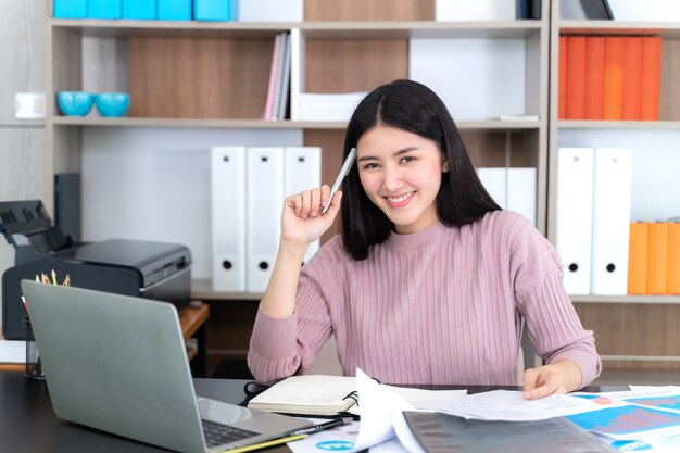 Estilo de vida hermosa mujer de negocios asiática joven usando la computadora portátil en el escritorio de oficina