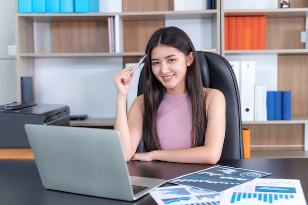 Estilo de vida hermosa mujer de negocios asiática joven usando la computadora portátil en el escritorio de oficina