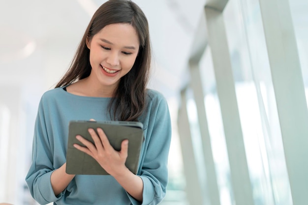 Estilo de vida nómada digital mujer asiática mujer mano usando tableta trabajando mientras se queda afuera con luz natural mujer joven asiática sonriendo alegre libertad sonrisa positiva pie mano sostener tableta