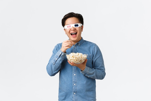 Estilo de vida de ocio y concepto de la gente alegre chico asiático sonriente en vasos d comiendo palomitas de maíz y ...