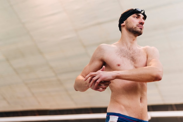 Foto gratuita estiramiento masculino joven antes de practicar natación