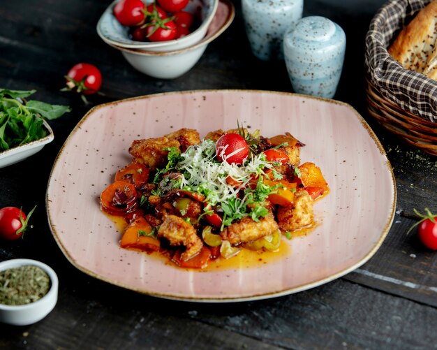 Estofado de pollo con verduras adornadas con hierbas, parmesano y tomate