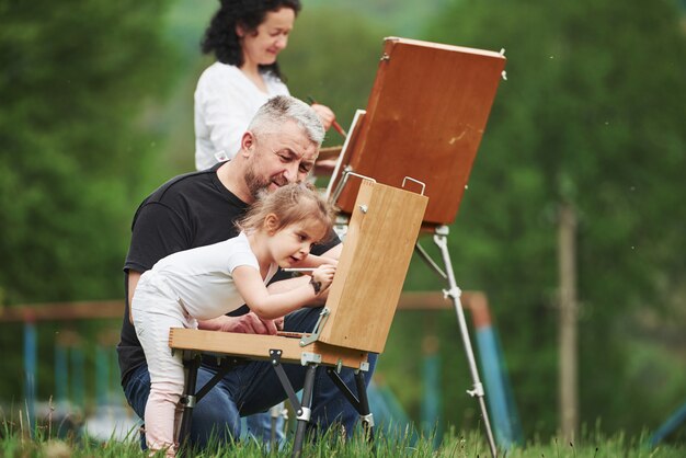 ¿Estoy haciendo eso bien? La abuela y el abuelo se divierten al aire libre con su nieta. Concepción de la pintura