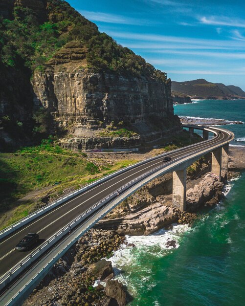 Una estrecha carretera con curvas con coches junto a montañas verdes