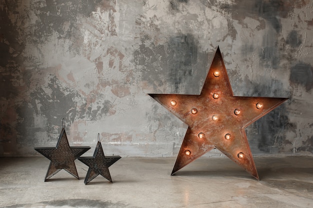 Foto gratuita estrella grande con luces de bombilla y una pequeña sobre fondo de muro de hormigón, decoración interior de loft.