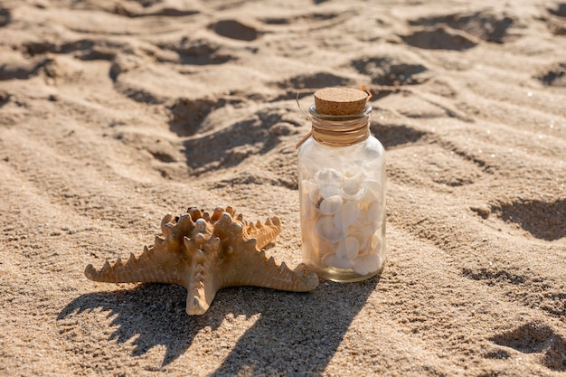 Foto gratuita estrella de mar y tarro de cristal con conchas en la arena