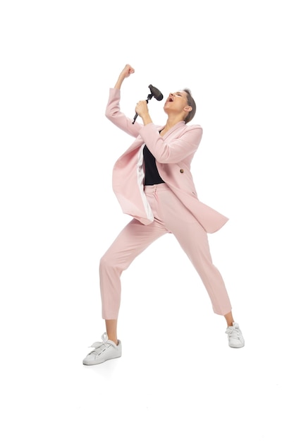 Estrella de rock. Mujer joven feliz bailando con ropa informal o traje, rehaciendo movimientos legendarios y bailes de celebridades de la historia de la cultura. Aislado. Acción, movimiento, concepto de fama. Ocupación creativa.