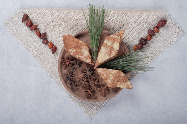 Estrellas de anís con tres pasteles dulces en placa de madera.