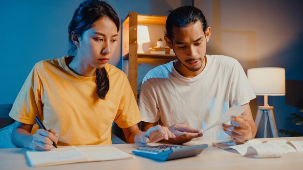 Estrés pareja asiática hombre y mujer usan la calculadora para calcular el presupuesto familiar