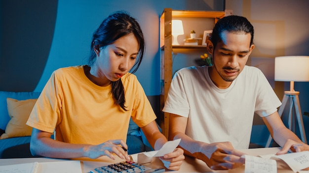 Estrés pareja asiática hombre y mujer usan la calculadora para calcular el presupuesto familiar