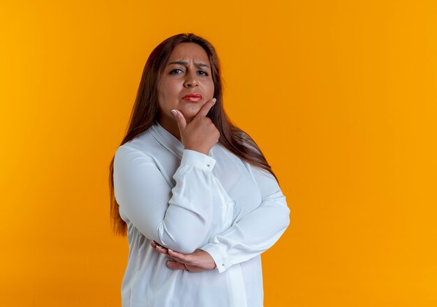 Estricta mujer de mediana edad caucásica casual poniendo la mano debajo de la barbilla aislada en la pared amarilla con espacio de copia