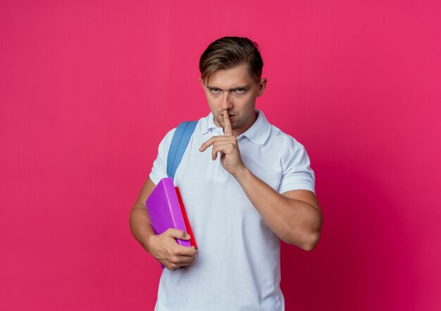 Estricto joven guapo estudiante vistiendo bolsa trasera sosteniendo libros