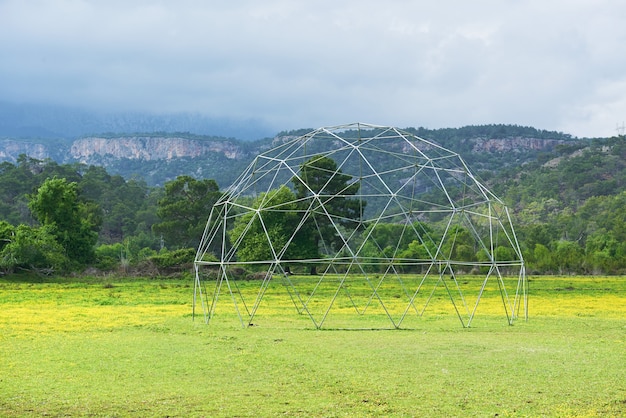 Estructura metálica sobre hierba verde y cielo azul.