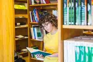 Foto gratuita estudiando mujer parada detrás de una estantería