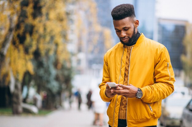 Estudiante afroamericano caminando en la calle y hablando por teléfono