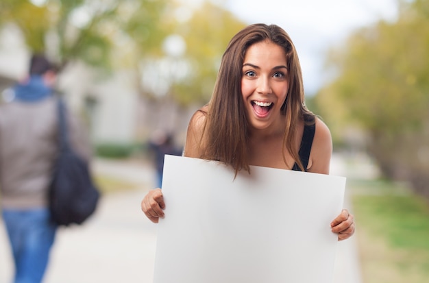 Foto gratuita estudiante alegre con un letrero en blanco