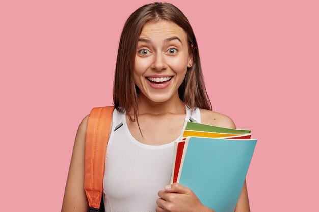 estudiante alegre posando contra la pared rosa