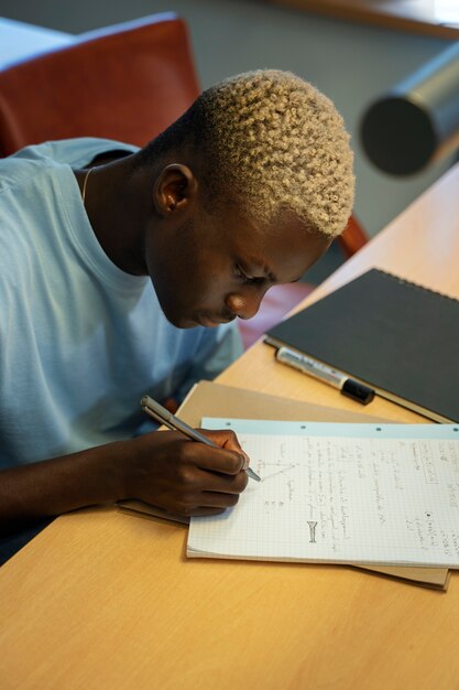 Estudiante de alto ángulo escribiendo en el cuaderno