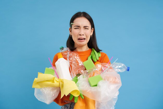 Una estudiante asiática triste sostiene que los desechos de reciclaje recolectan basura plástica para llevarla al centro de reciclaje