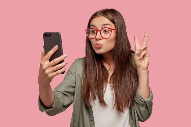 Estudiante de aspecto agradable posando contra la pared rosa