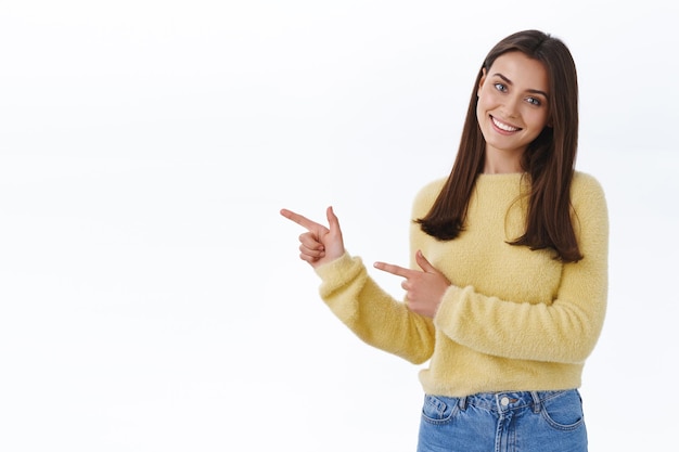 Foto gratuita estudiante de aspecto amistoso que le muestra el camino, apuntando con el dedo hacia el banner promocional, espacio de copia en blanco en blanco para su anuncio como recomendación