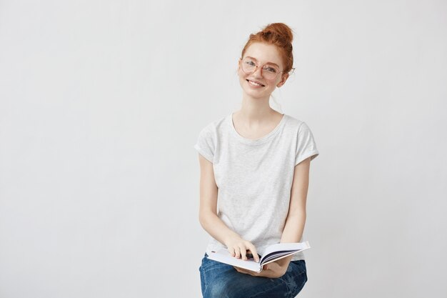 estudiante astuto sonriendo sosteniendo portátil.