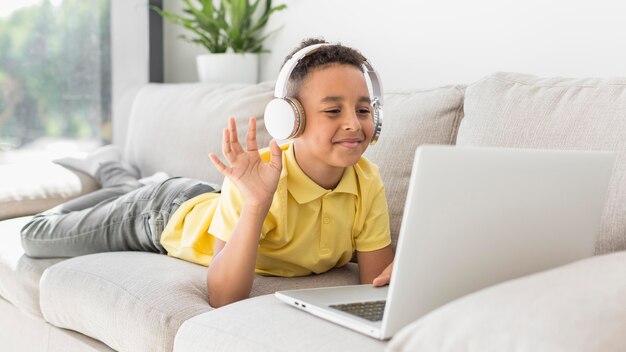 Estudiante con auriculares saludando a laptop