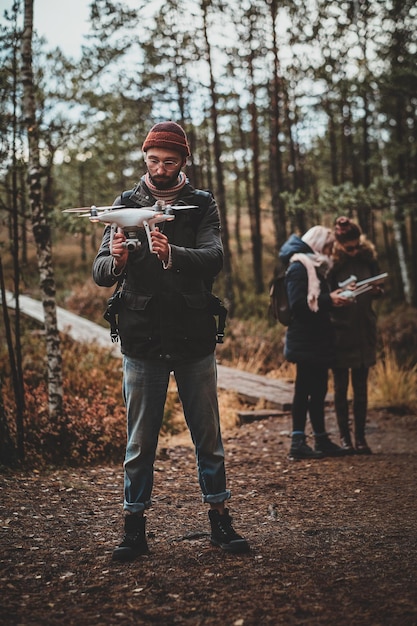 Un estudiante barbudo está haciendo una foto con su dron, mientras sus amigos miran algo en la tableta.