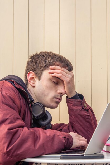 Un estudiante cansado está estudiando usando una computadora portátil Estudiante masculino estudiando en línea