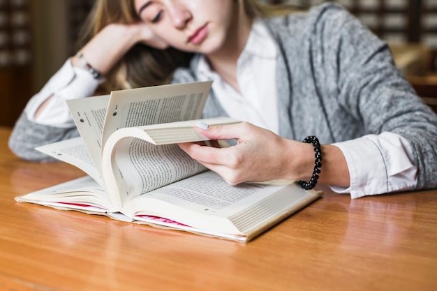 Estudiante cansado volteando páginas de libros