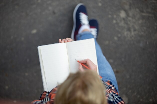 Estudiante chica escribiendo con un lápiz en un cuaderno