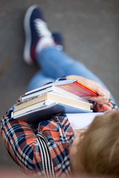 Estudiante chica con un montón de libros de texto y cuadernos