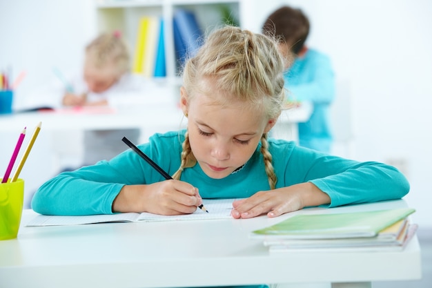 Foto gratuita estudiante concentrada escribiendo en su cuaderno