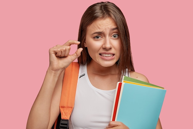 Foto gratuita estudiante desconcertado posando contra la pared rosa