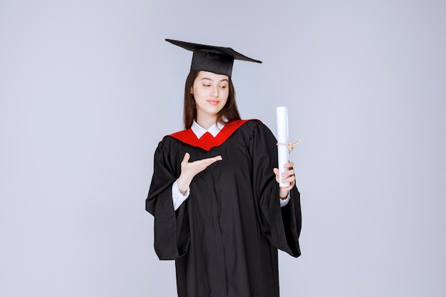 Estudiante con diploma universitario posando para la cámara. Foto de alta calidad