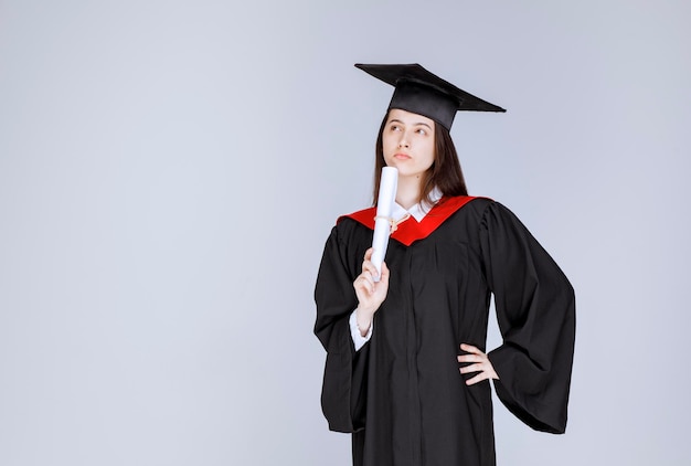 Estudiante con diploma universitario posando para la cámara. Foto de alta calidad