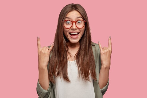 Estudiante emocionado posando contra la pared rosa