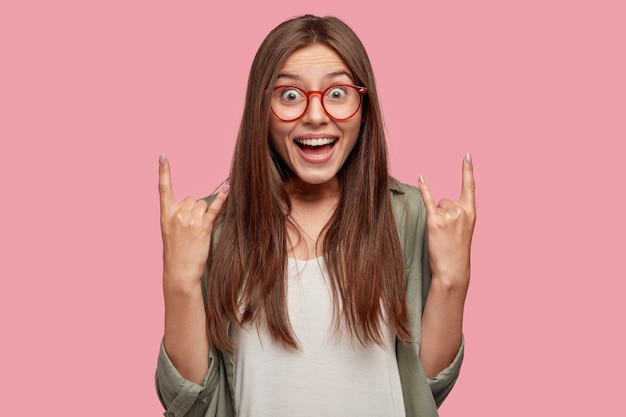 Estudiante emocionado posando contra la pared rosa