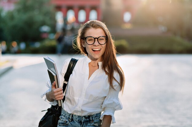 Estudiante encantador feliz en camisa blanca preparándose para estudiar