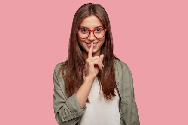 Estudiante encantador misterioso posando contra la pared rosa