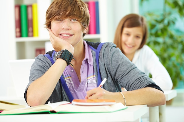 Estudiante escribiendo y tocándose la cara